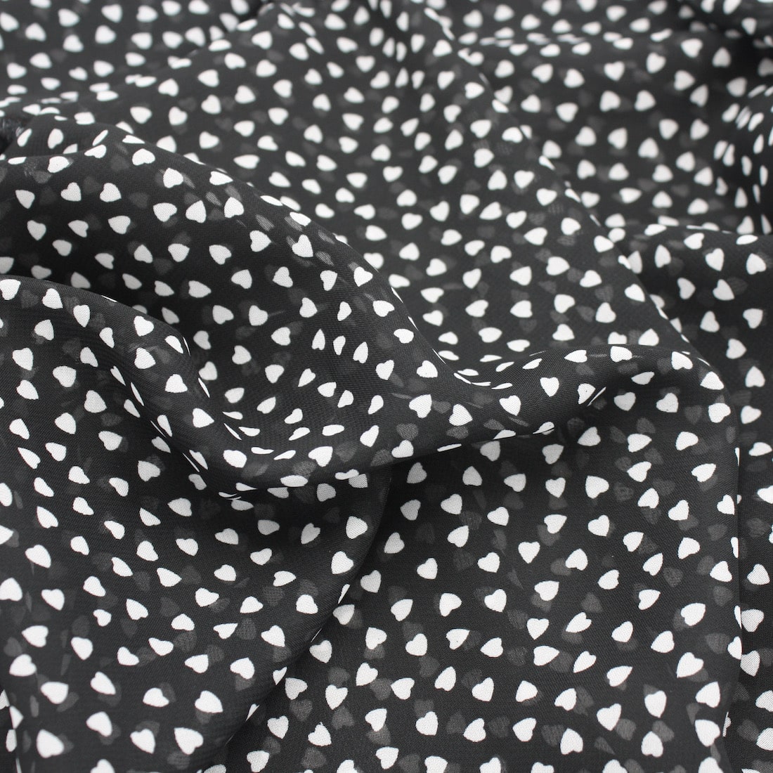 Chiffon fabric with small white hearts on black background