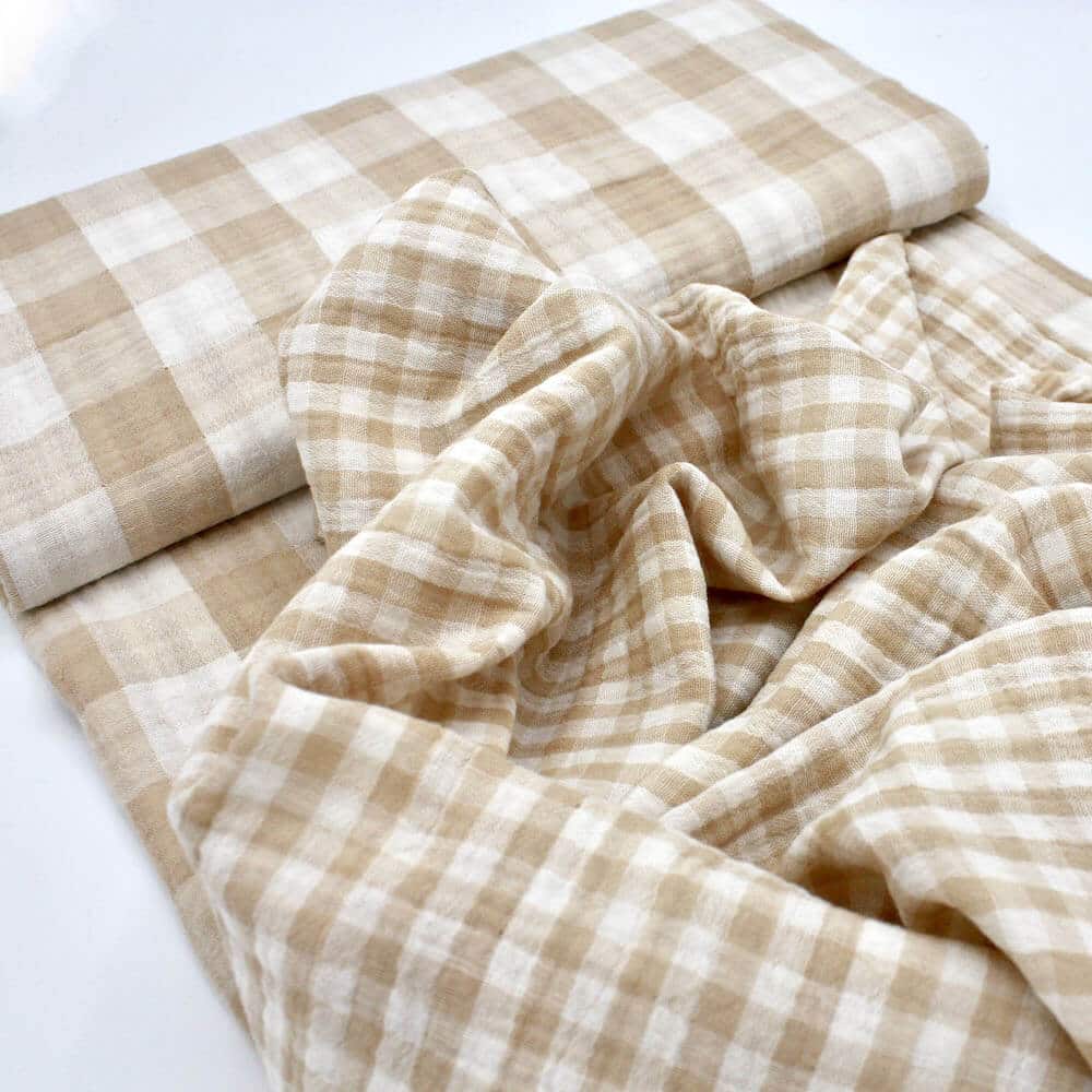 bolt of sand coloured double gauze gingham fabric showing two sizes of check gingham
