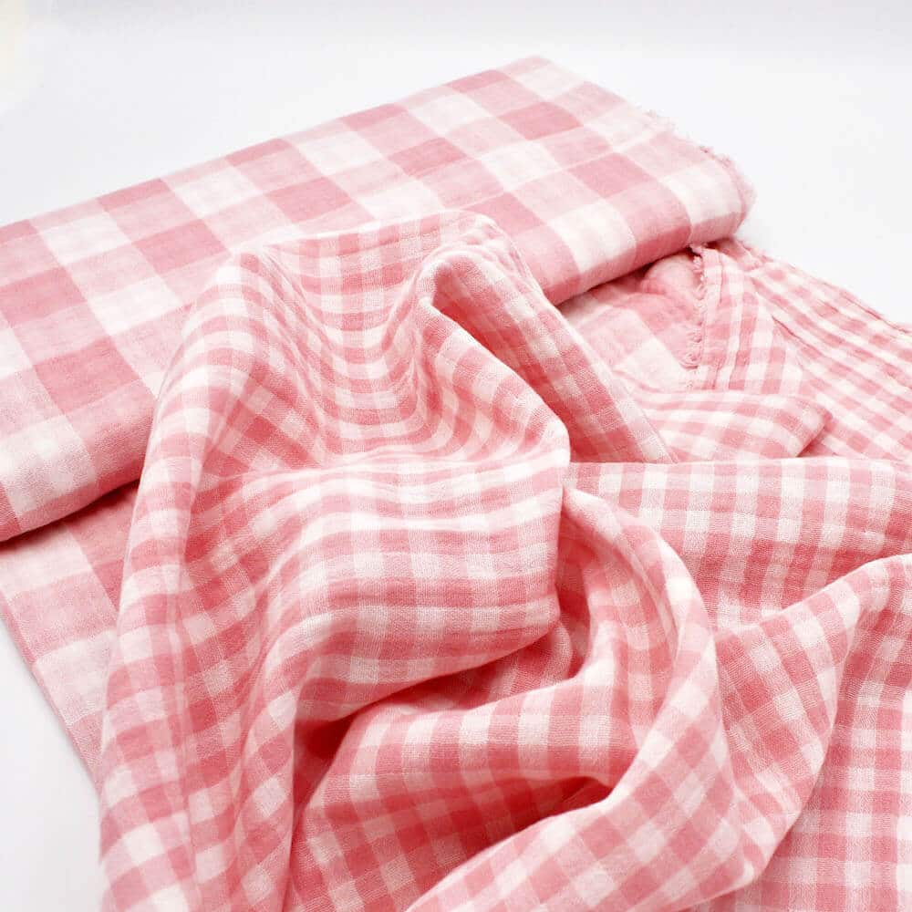 bolt of gingham double gauze in soft pink showing both sides of the fabric.