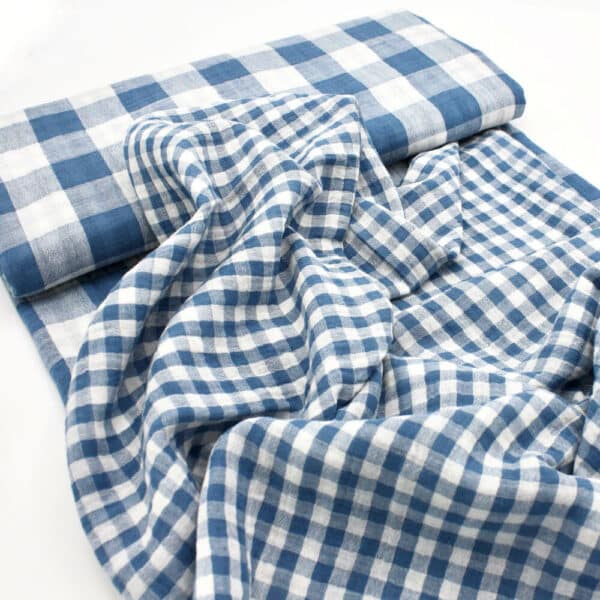 bolt of gingham double gauze fabric in blue showing both sides of fabric