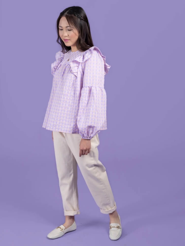 young girl wearing a lilac smock top and cream trousers