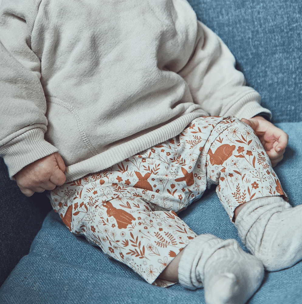 sitting toddler wearing a childs printed trousers and white sweatshirt