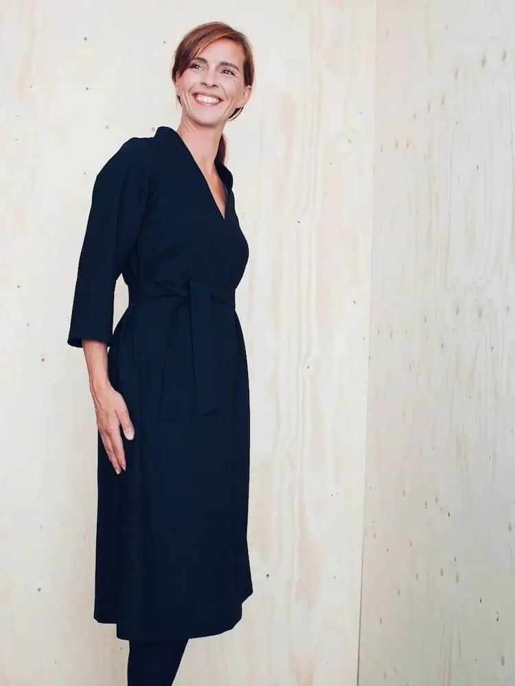 lady standing side on wearing a knee length black shirt dress with three quarter sleeves