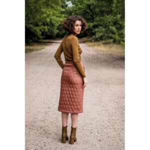 lady standing on a road looking back wearing a rust quilted skirt