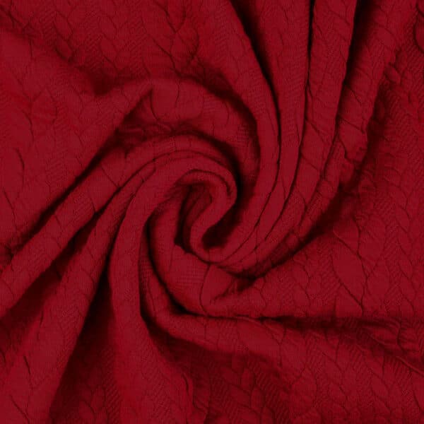 Deep red cable knit jersey fabric in a swirl