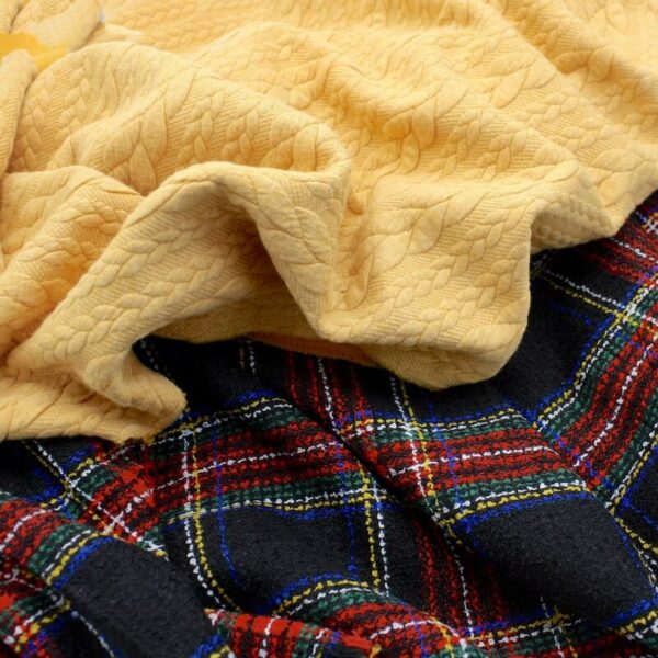 Close up of royal steward black tartan boucle fabric and yellow cable knit folded together show a good match Image 2