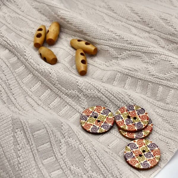 Cream jacquard cable knit fabric with buttons zoomed in