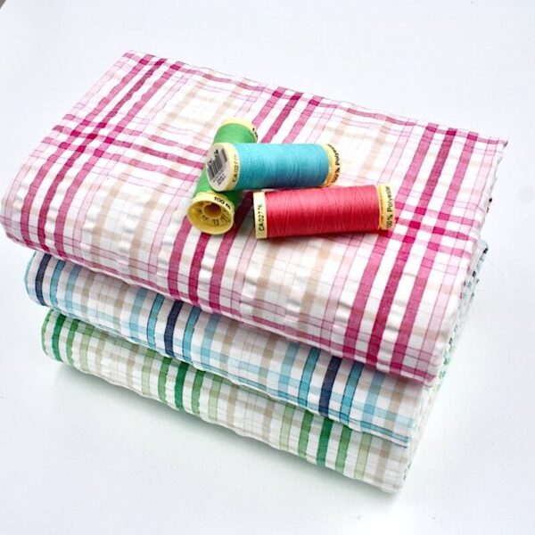 Bundle of seersucker gingham fabric with matching threads on top