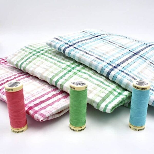 Bundle of seersucker gingham fabric with matching threads in front